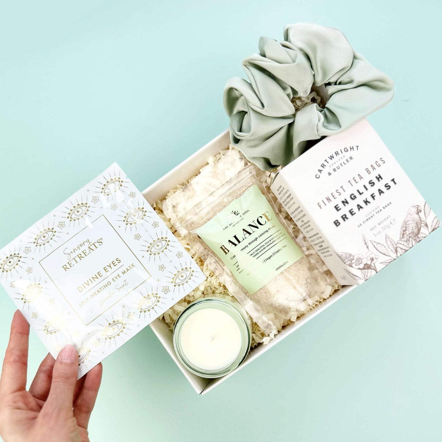 Gift set with a candle, soap, and scrunchies on a light blue background