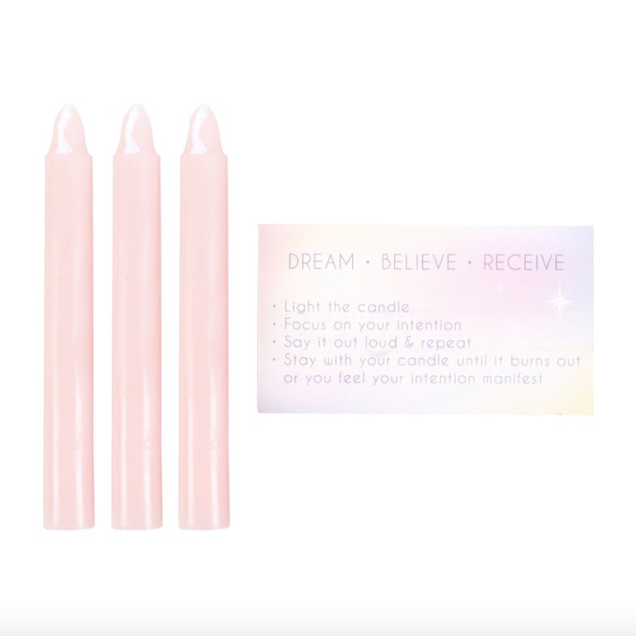 Three pink candles with a card on a white background