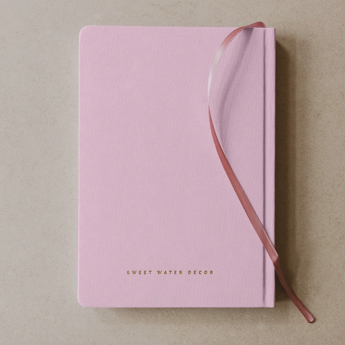 Pink notebook with a ribbon on a beige background