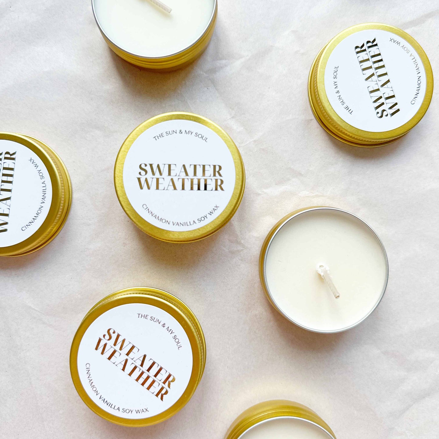 Candle tins labeled 'Sweater Weather' on a light background