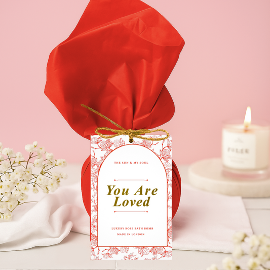 Product wrapped in red paper with a 'You Are Loved' label on a pink background