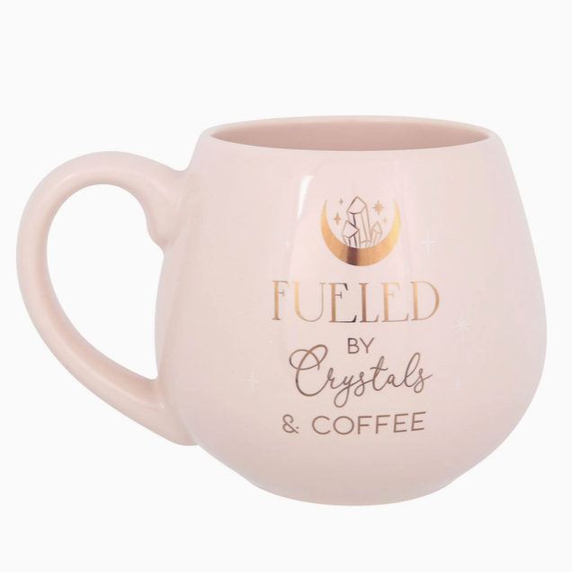 Pink mug with 'Fueled by Crystals & Coffee' text on a white background