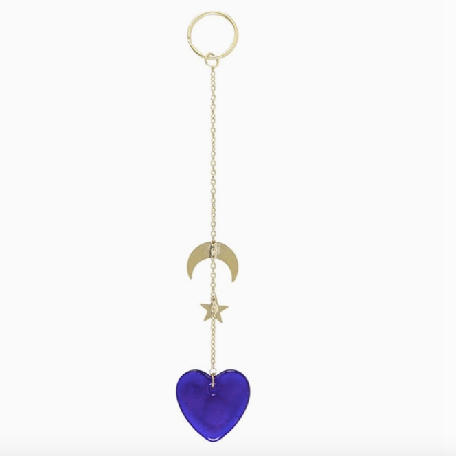 Blue heart-shaped keychain with gold chain and moon and star charms on a white background
