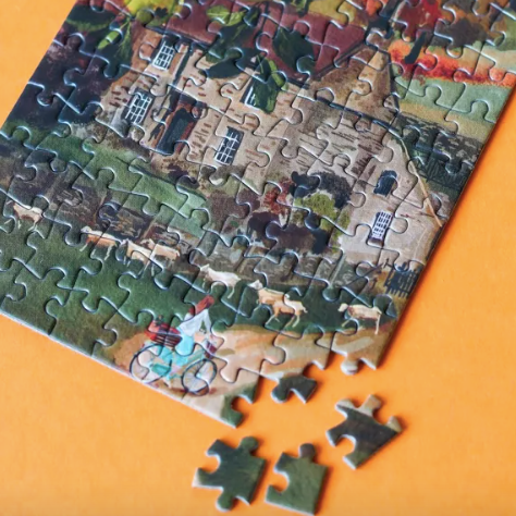 Jigsaw puzzle with a completed section of 'English Cottage' on an orange background