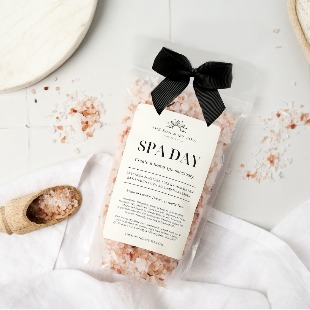 Bag of pink Himalayan salt with a black ribbon on a white surface
