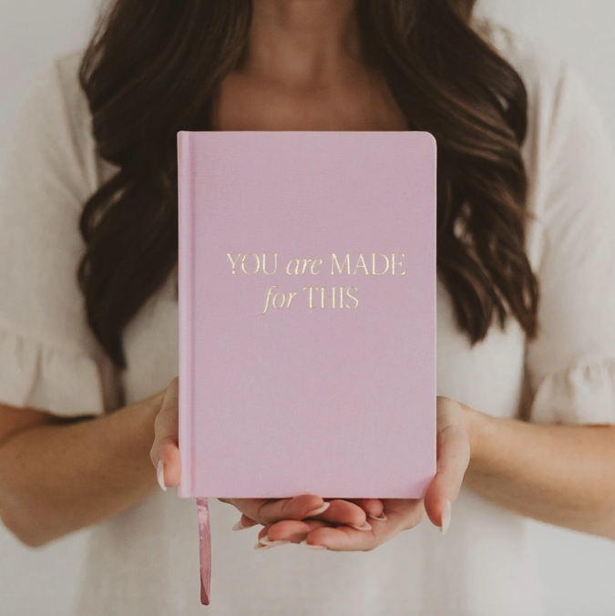 Person holding a pink notebook with 'YOU are MADE for THIS' text.