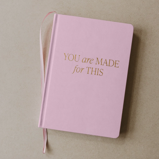 Pink notebook with 'YOU are MADE for THIS' text on a beige background