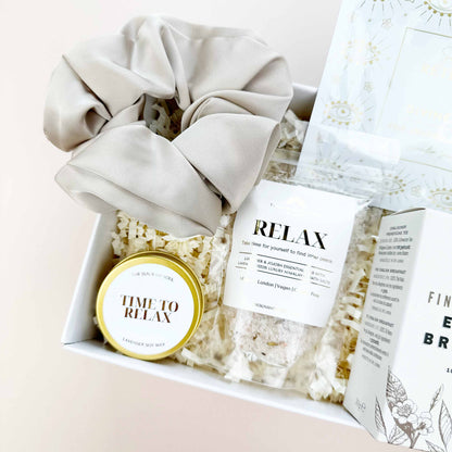 Gift set with scrunchies, popcorn, and a 'Time to Relax' candle on a light background