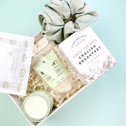 Gift box with a candle, tea, and bath product on a light blue background