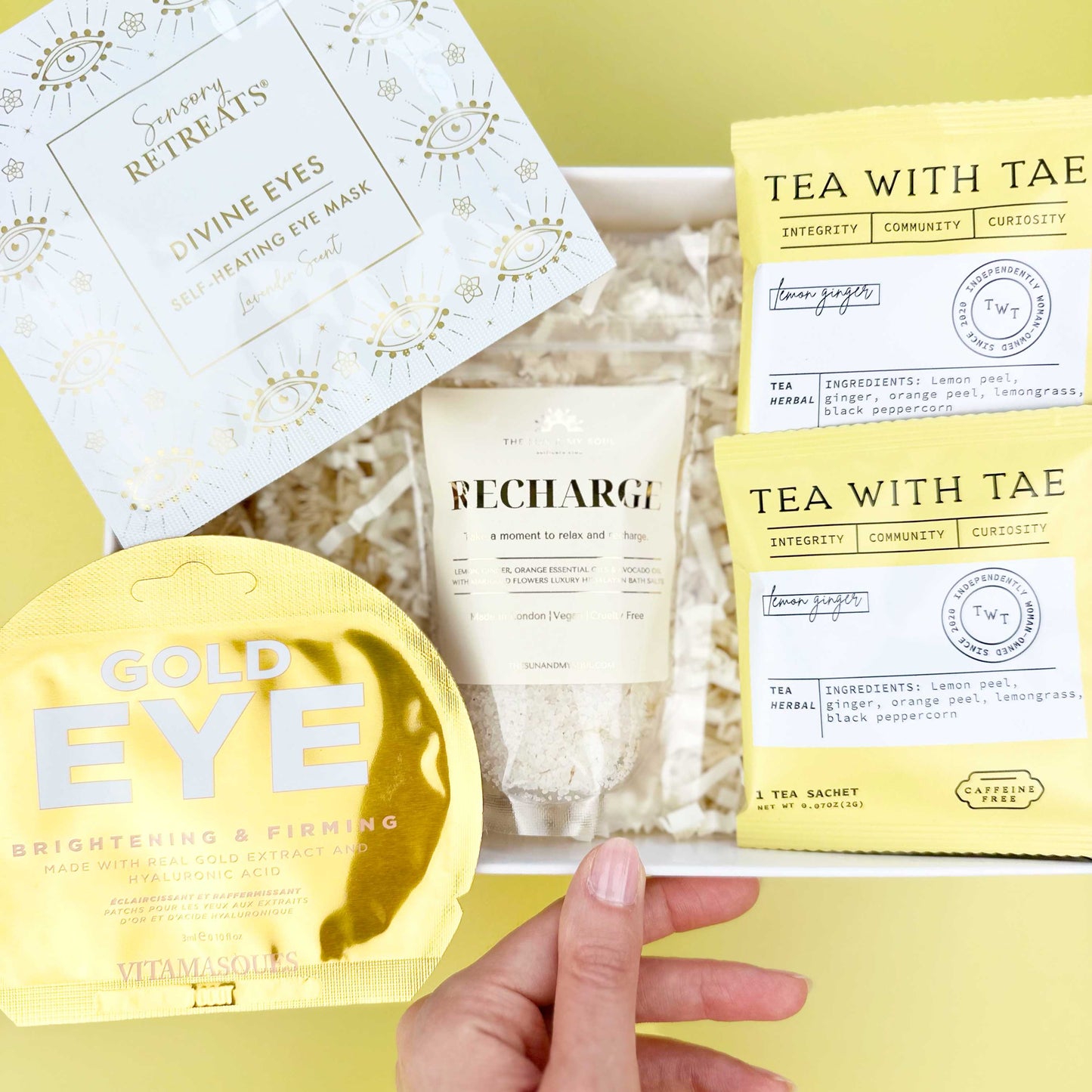 Collection of skincare products including eye masks and tea bags on a yellow background