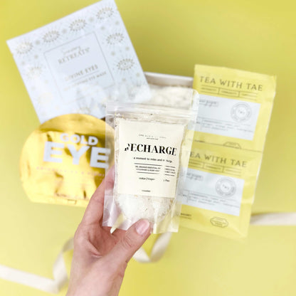 Hand holding a skincare product with 'Tea With Tea' packaging on a yellow background