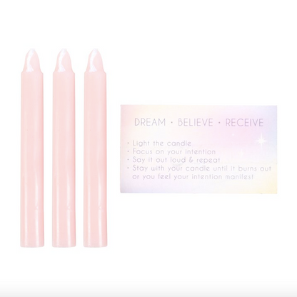 Three pink candles with a card on a white background