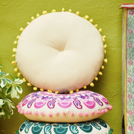 Stack of decorative cushions with colorful patterns against a green wall.