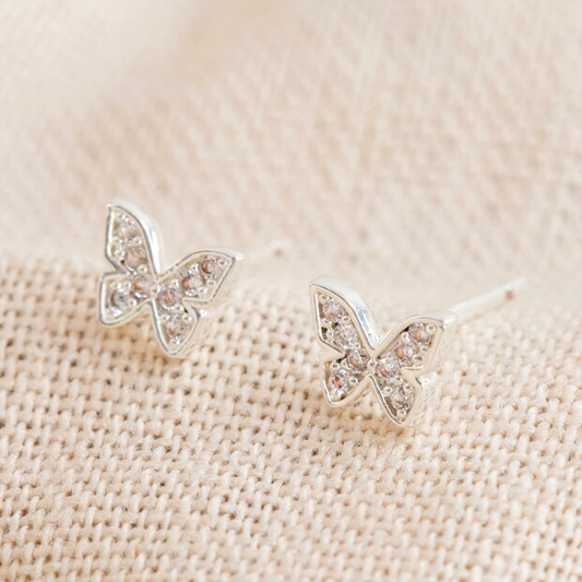 Butterfly-shaped earrings on a beige fabric background