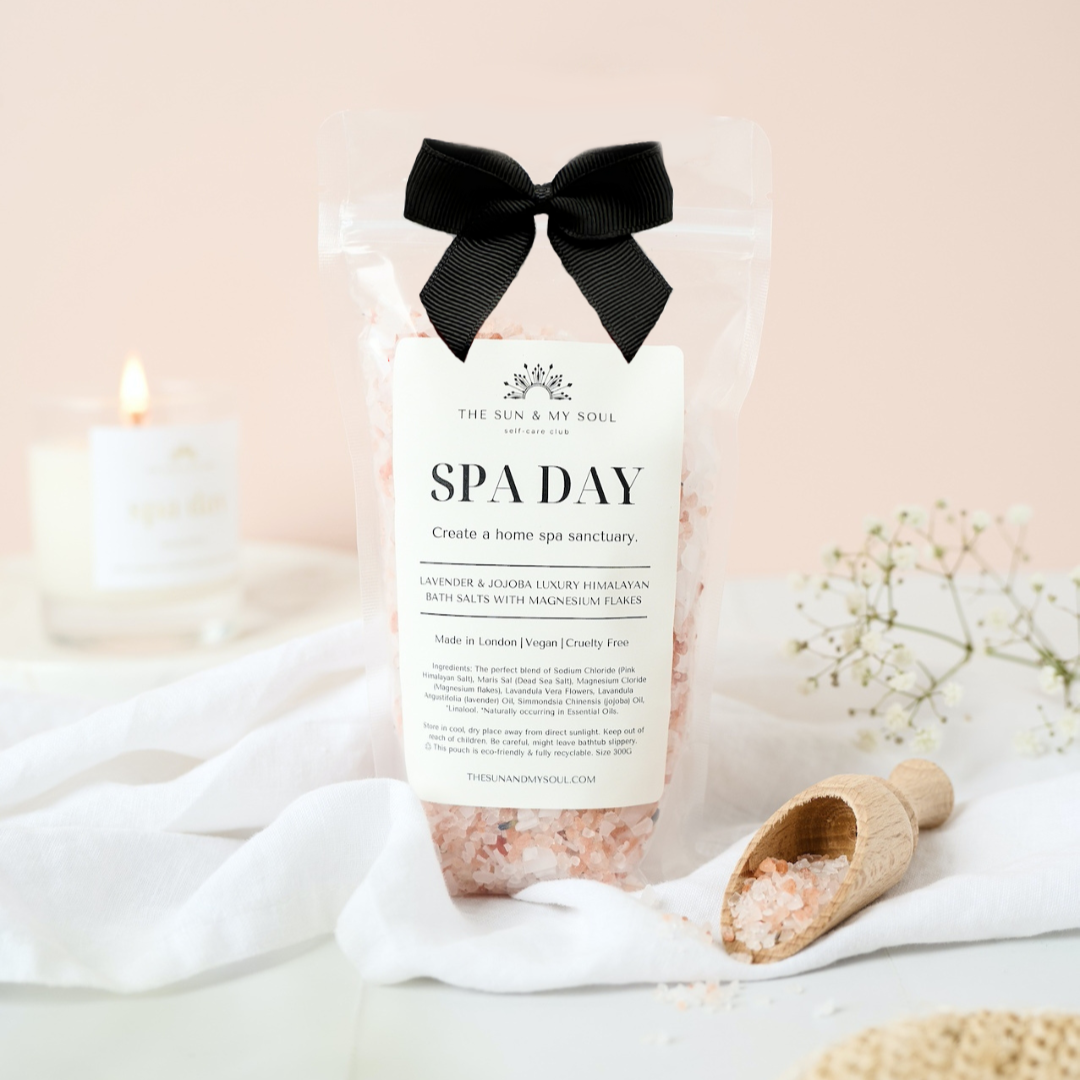 Spa day product with a black bow, candle, and bath accessories on a soft background