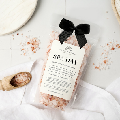 Bag of pink Himalayan salt with a black ribbon on a white surface